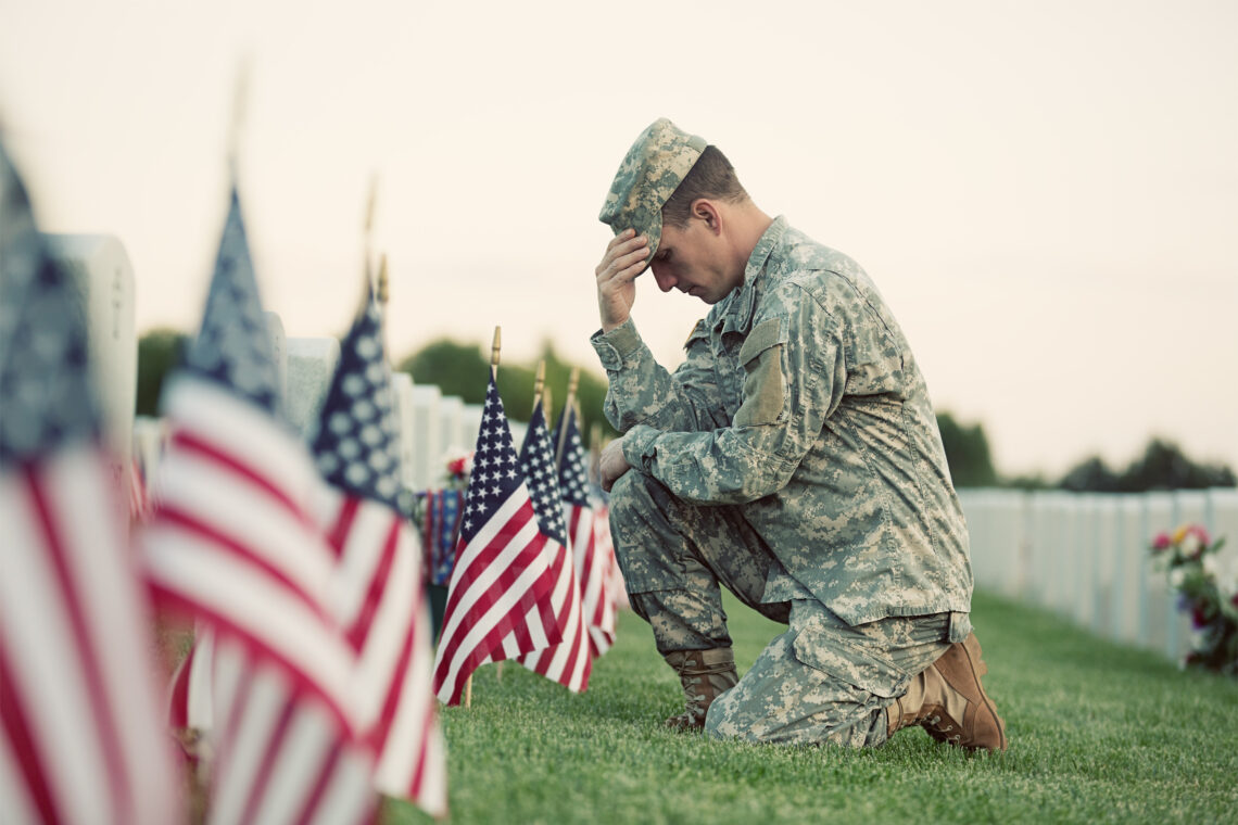 Soldier kneeling at grave Corbally, Gartland and Rappleyea, LLP